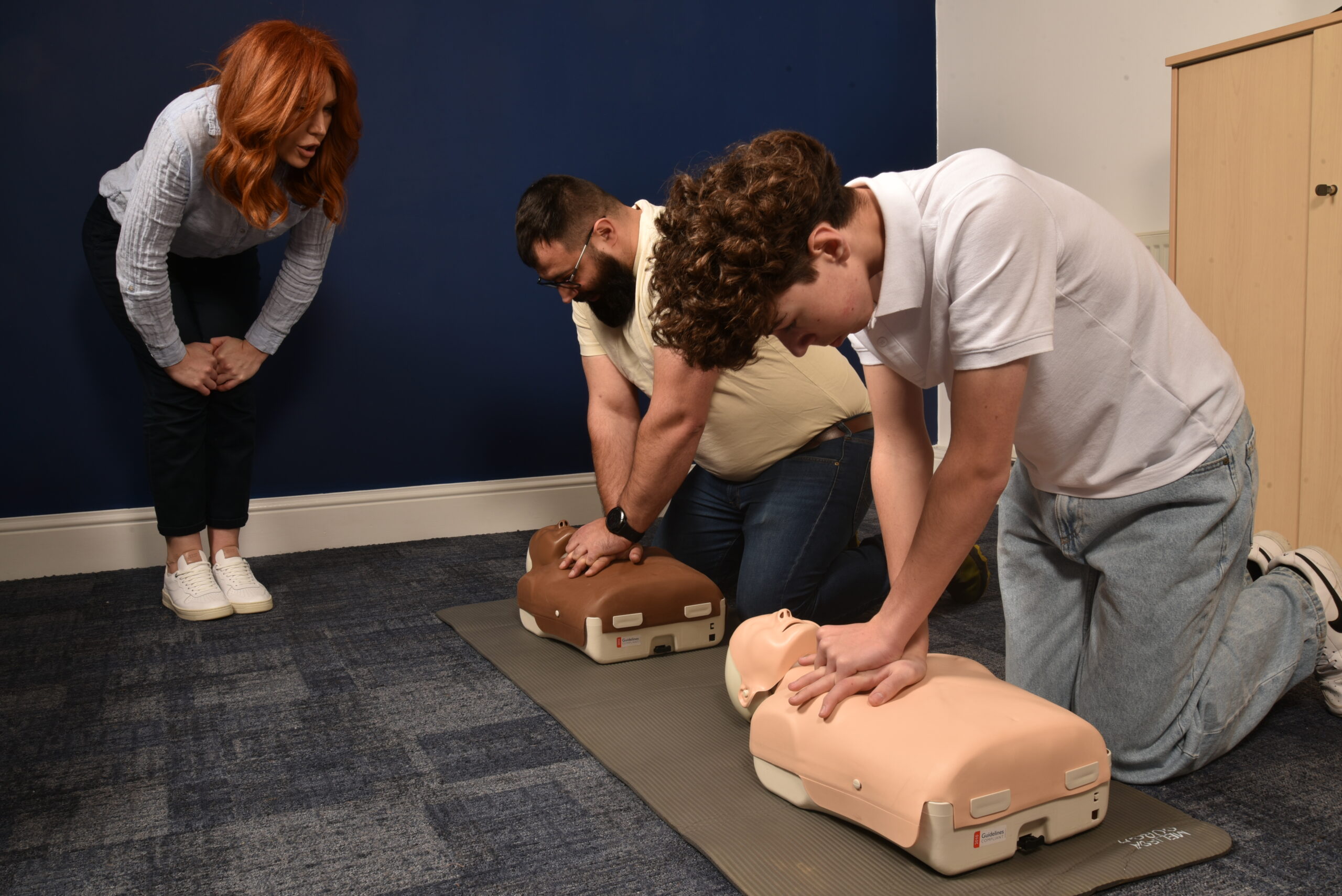 Instructor teaching how to perform CPR on a mannequin during a first aid training course.